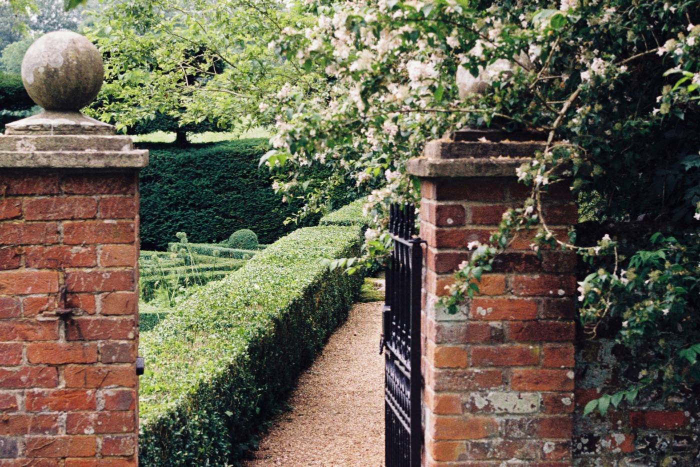 An open garden gate between brick piers