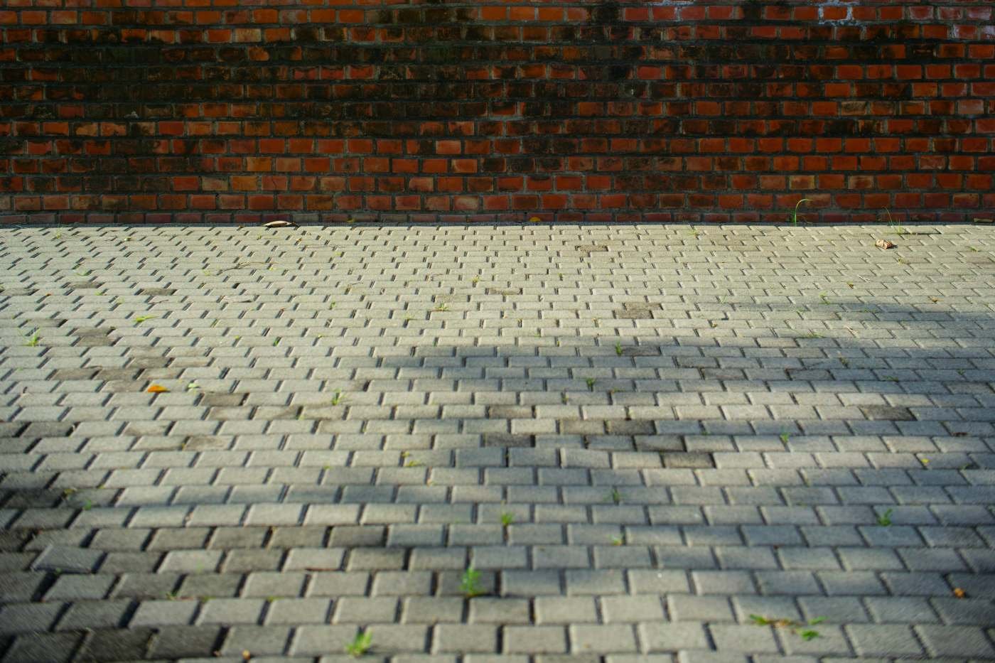 Grey block paving in front of a brick wall