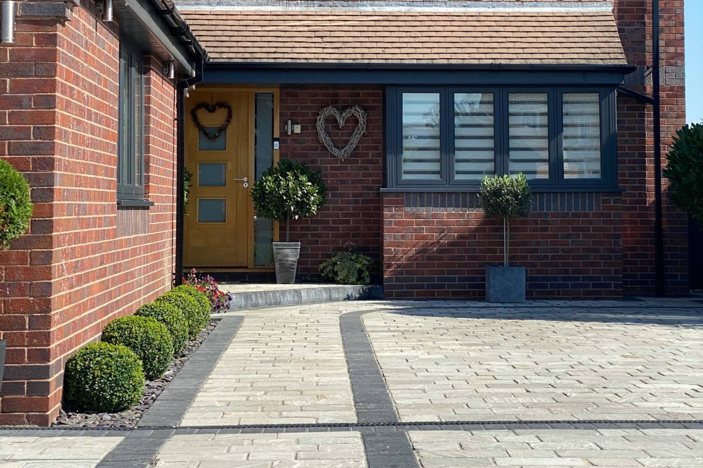 A block-paved driveway in front of a red-brick house